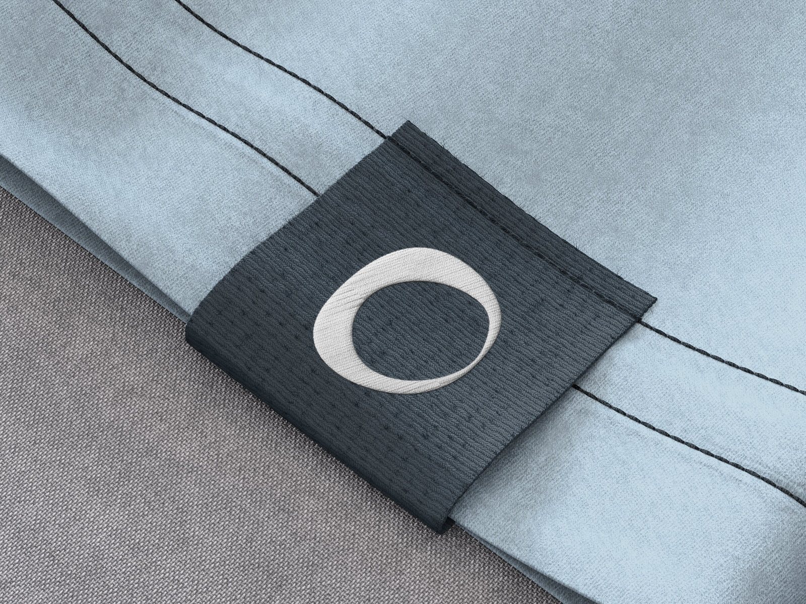 Étiquette tissée ardoise à l'icône « O » de Joiia, sur un chandail bleu pâle