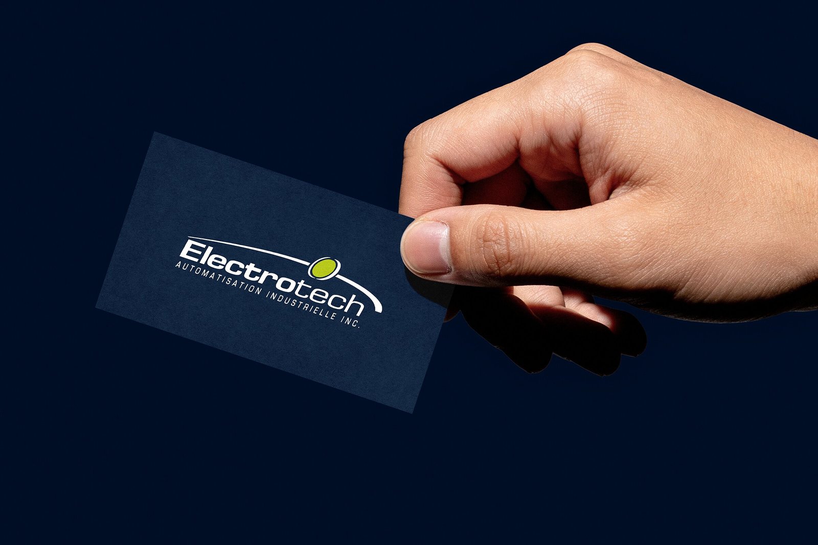 Carte d'affaires d'Electrotech tenue en main, logo blanc sur fond bleu nuit