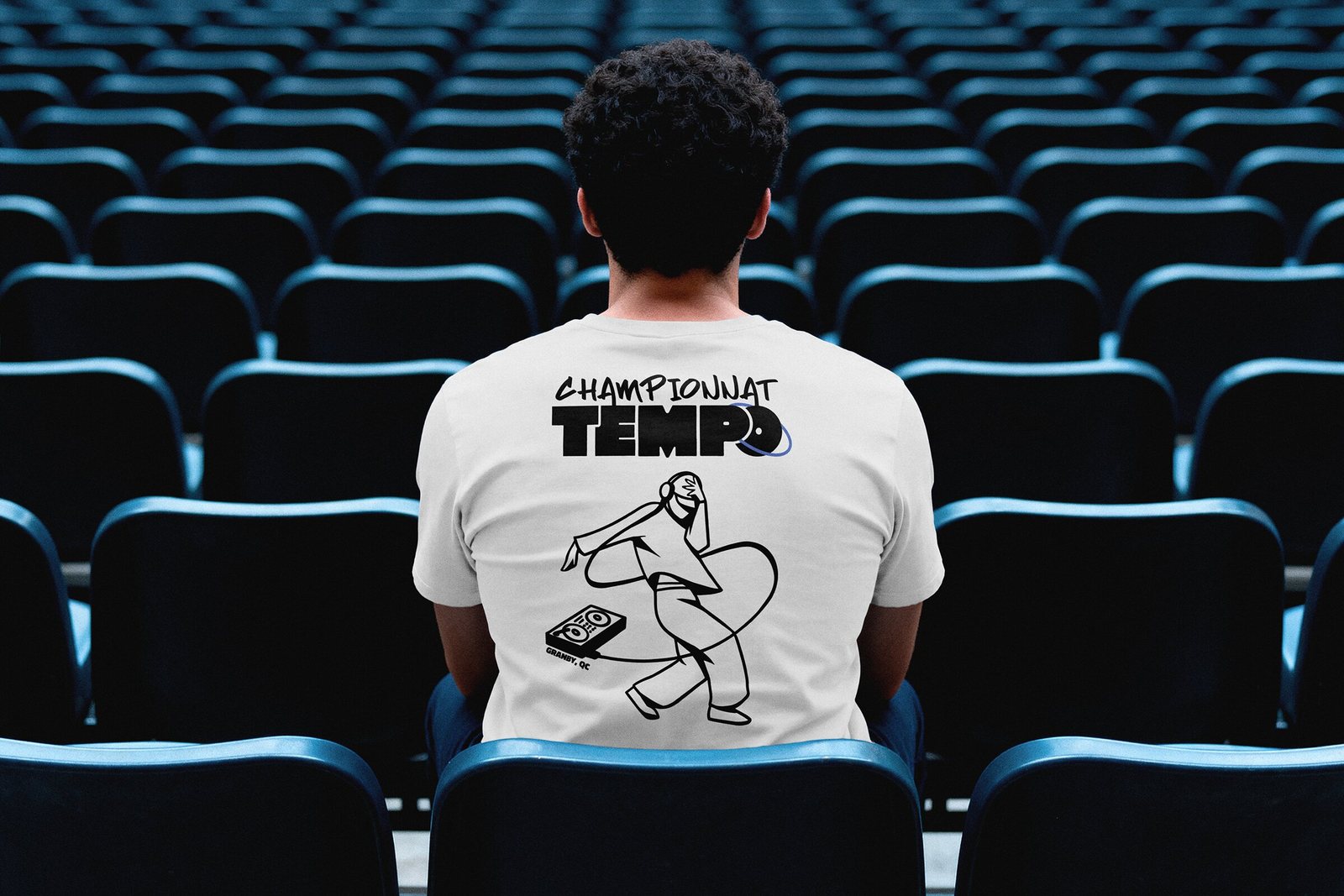 Spectateur de dos dans des gradins, en t-shirt blanc « Championnat Tempo » avec la mascotte